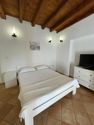 a white bedroom with a bed and a tv at Studio Apartment Ana in Vrsar