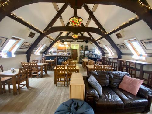 een woonkamer met een bank en tafels en stoelen bij Inversnaid Bunkhouse in Inversnaid