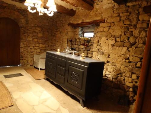 Cette chambre est dotée d'un mur en pierre et d'une commode. dans l'établissement Le Clos du Tilleul, à Saint-Michel-lʼObservatoire