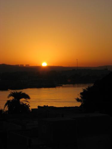 a sunset over a river with the sun in the distance at Bet El Kerem Guesthouse in Aswan