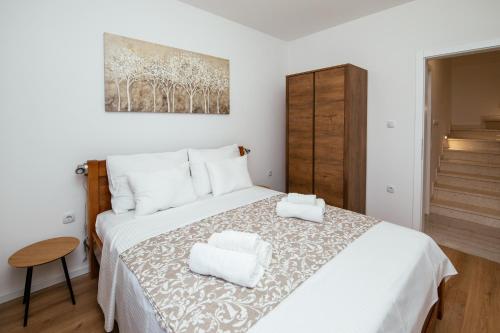 a bedroom with a white bed with two towels on it at Family house Moja jube in Oklaj