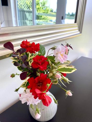 a vase filled with red and white flowers on a table at A secluded self contained Country Suite with a view - parking, easy access to Bath in Corsham