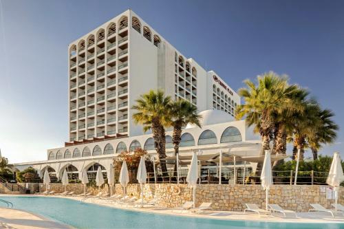 a hotel with a swimming pool in front of a building at Crowne Plaza Vilamoura - Algarve by IHG in Vilamoura