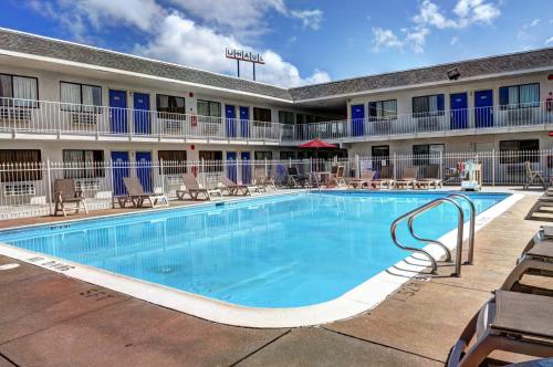 einen Pool vor einem Hotel mit Tischen und Stühlen in der Unterkunft Motel 6-Slidell, LA - New Orleans in Slidell