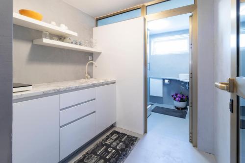 a white kitchen with a sink and a bathroom at Apartment Porin in Velika Gorica