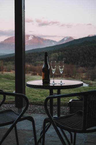 a table with two glasses and a bottle of wine at Frances' Sketch Pad with Hot Tub in Fort William
