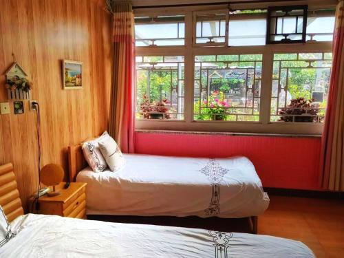 two beds in a room with a window at Beijing Badaling Great Wall Caos Courtyard Hostel 1Private english tour guide 2Pick up&Drof off &landmark visiting serivice3Very near to Badaling Great Wall4Offer free beijing travel guide5Traditonal Chinese courtyard in Yanqing