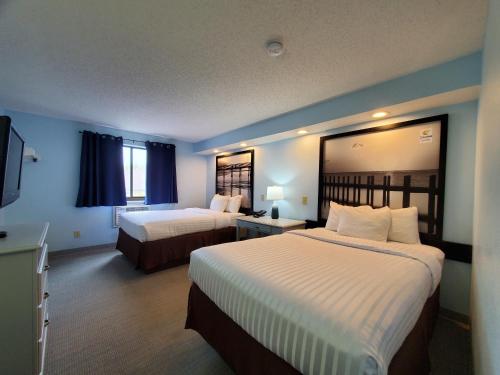 a hotel room with two beds and a television at Coastal Inn & Suites in Wilmington