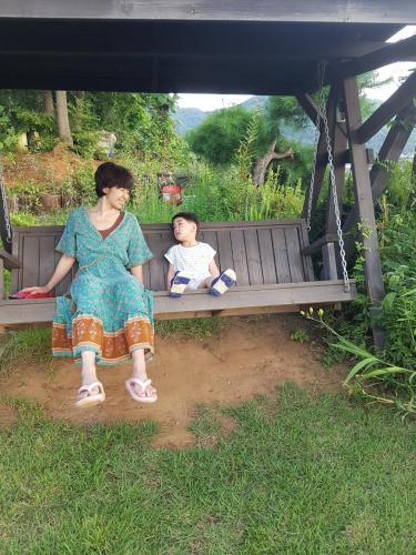 a woman and a child sitting on a bench at Walking Sky Pension in Gapyeong