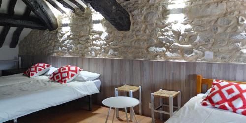 Habitación con 2 camas y pared de piedra. en Albergue El Condor, en Paúles