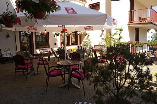 a patio with tables and chairs and a white umbrella at Hotel Ottaviano in Świnoujście