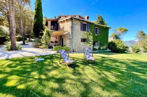 duas cadeiras na relva em frente a uma casa em La Panoramica Gubbio - Maison de Charme - Casette e appartamenti self catering per vacanze meravigliose! em Gubbio