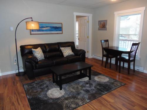 a living room with a leather couch and a table at Strictly Moose Luxury Vacation Suites in Gorham