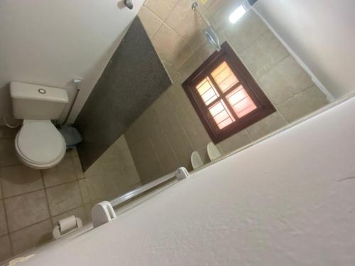 La salle de bains est pourvue de toilettes et d'une fenêtre. dans l'établissement Apartamento Village do Bosque - a 200 metros da praia, à Porto Seguro