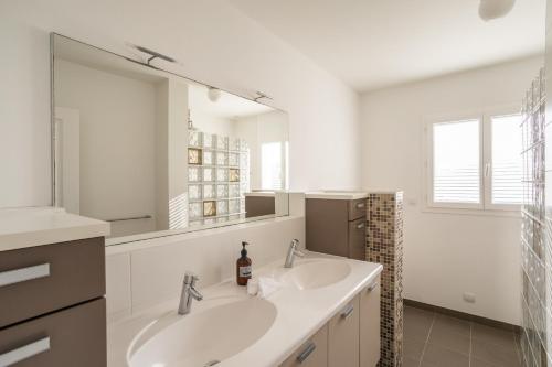 un bagno con due lavandini e un grande specchio di La Baie Blanche - Maison contemporaine à Saint-Cast-Le-Guildo a Saint-Cast-le-Guildo