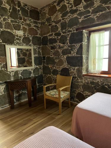 a room with a stone wall with a table and a chair at Casa rural con baño adaptado y piscina en Mogán in Mogán