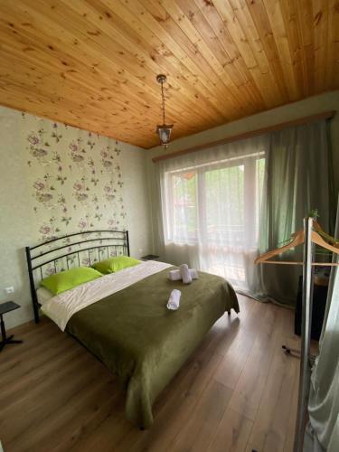 a bedroom with a bed with green sheets and a wooden ceiling at WATERFALL in Stepantsminda