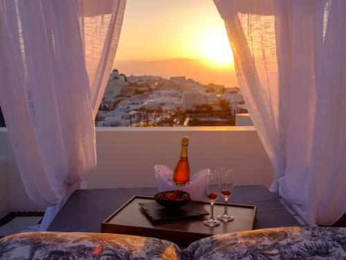 a table with two glasses and a bottle of wine at Nikos Villas in Oia