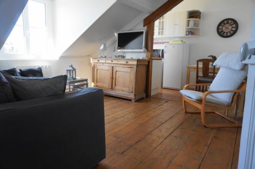 - un salon avec un canapé et une télévision dans l'établissement Le Proust sans souci, à Cabourg