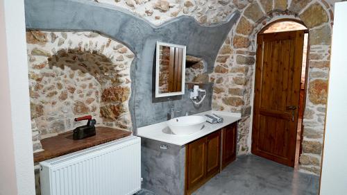 uma casa de banho em pedra com um lavatório e um espelho em Stone Residence Chios em Quios