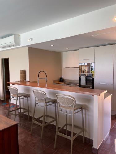 a kitchen with a large island with bar stools at Les Villas du Lagon in Le François