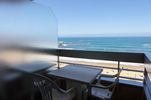 a table and chairs on a balcony with the ocean at Résidence Victoria Surf in Biarritz