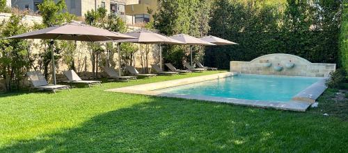 una piscina con sillas y sombrillas en un patio en Chiostro dei Domenicani - Dimora Storica, en Lecce