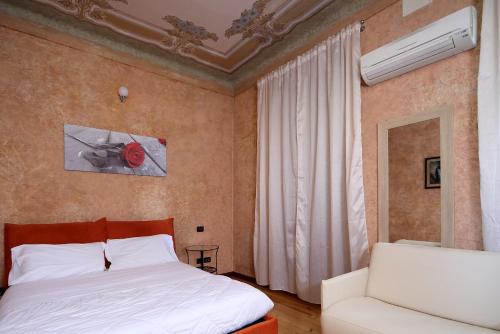 a bedroom with a white bed and a white couch at Appartamento liberty con area giochi in Udine