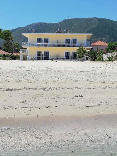 a white building on the beach with the sand at Anatolikos Rooms in Alykes