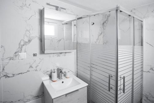 een witte badkamer met een wastafel en een douche bij MG apartments in Alexandroupoli