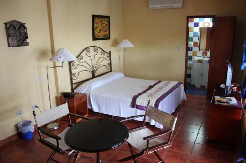 a bedroom with a bed and a table and chairs at Hotel Los Arcos in Estelí