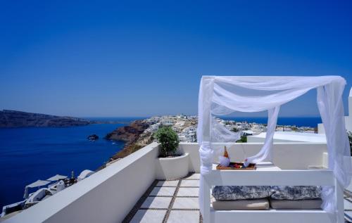 a white gazebo on a balcony overlooking the ocean at Nikos Villas in Oia