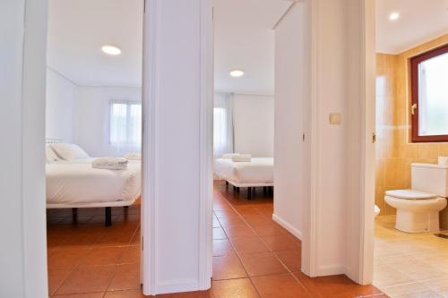 a room with two beds and a bathroom with a toilet at Abba Comillas Apartments in Comillas