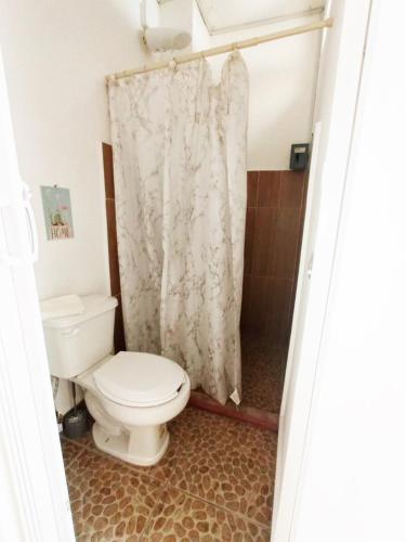 a bathroom with a toilet and a shower curtain at La Maja Suites in Villahermosa
