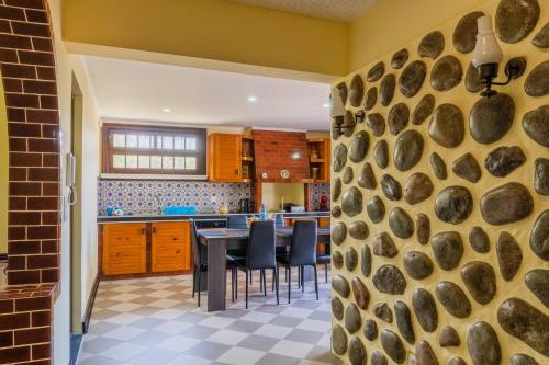 a kitchen with a stone wall and a table with chairs at Pinheiro SUN&BEACH House in Ponta Delgada