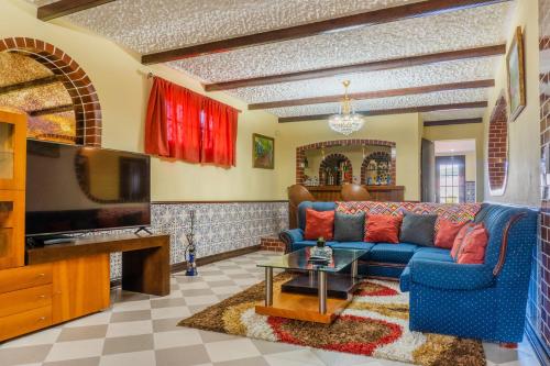 a living room with a blue couch and a tv at Pinheiro SUN&BEACH House in Ponta Delgada