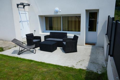 un patio con divano e sedie di fronte a un edificio di Nouveau - studio aux portes de Brest a Bohars