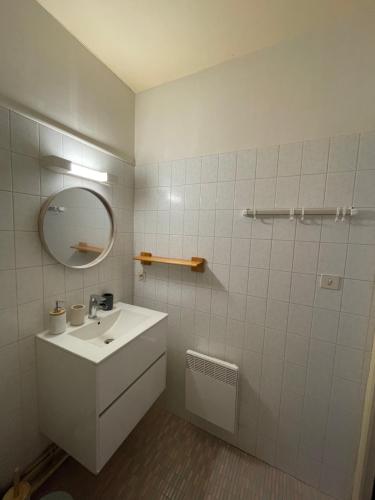 a white bathroom with a sink and a mirror at Superbe Appartement au bord de la rivière in Ax-les-Thermes