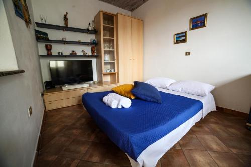 1 dormitorio con 1 cama con sábanas azules y TV en Il Quattro, en Alghero