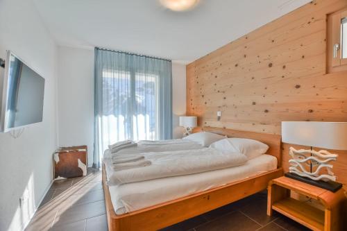 a bedroom with a large bed with a wooden wall at Stella 5 in Riederalp