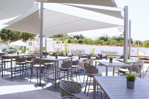 a patio with tables and chairs under a white umbrella at Kapetanios Bay Hotel Protaras in Protaras