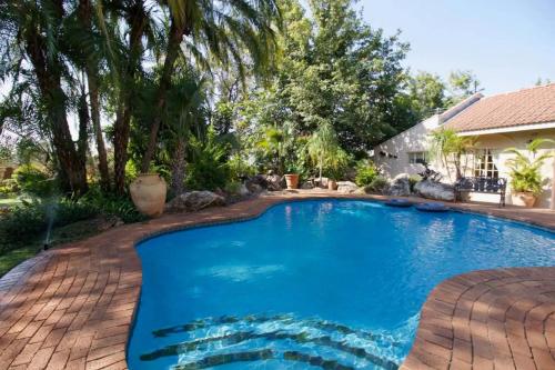 una piscina con un patio de ladrillo y una casa en Wonderfully spacious two bedroom cottage in a quiet secluded area of town, on the edge of the bush - 1998, en Victoria Falls