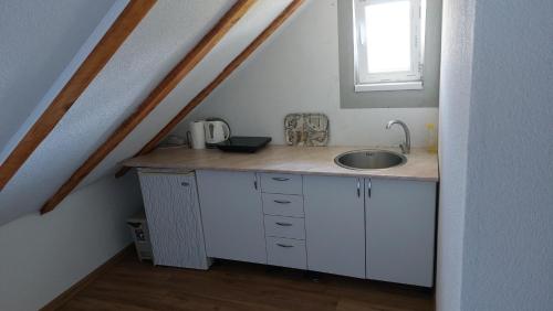 une cuisine avec un évier et une fenêtre dans l'établissement Apartments Alibasic, à Dubrave Gornje