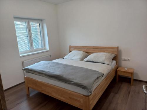 a bedroom with a wooden bed with two pillows at apartmán Sedmička Frymburk in Frymburk