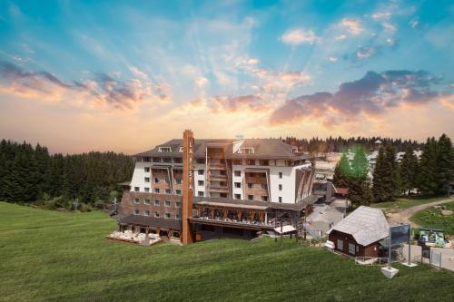 a large building on a hill with a green field at Gorski Hotel & Spa in Kopaonik