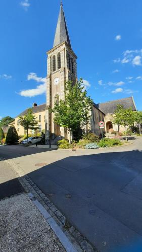 a church with a tower with a clock on it at La Ménagerie in Maigné