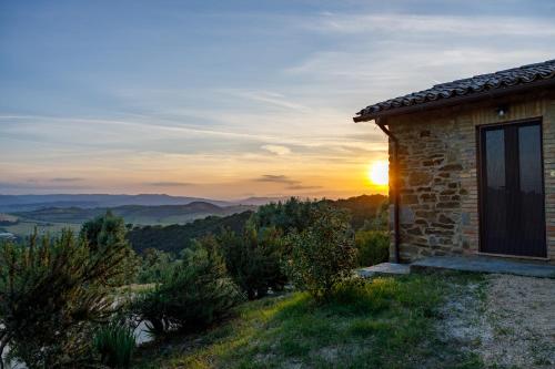 a stone house on a hill with the sunset in the background at Antichi Casali di Charme in Orvieto