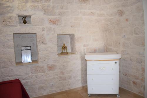 a bathroom with a toilet and a stone wall at Dimora Domrose in Locorotondo