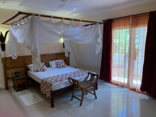 a bedroom with a bed with a canopy and a chair at Le Lodge des Almadies in Dakar