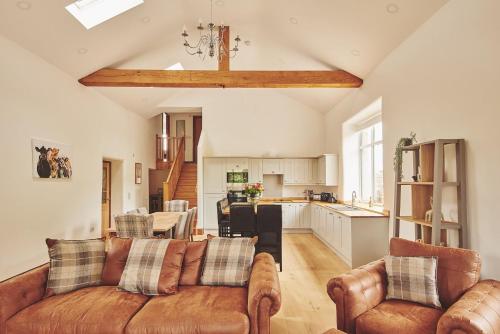 a living room with a couch and a kitchen at Plum Cottage in Appleby